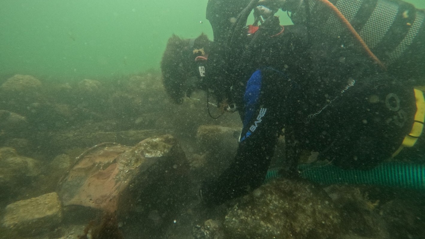 A student is excavating a copper cauldron in the galley area