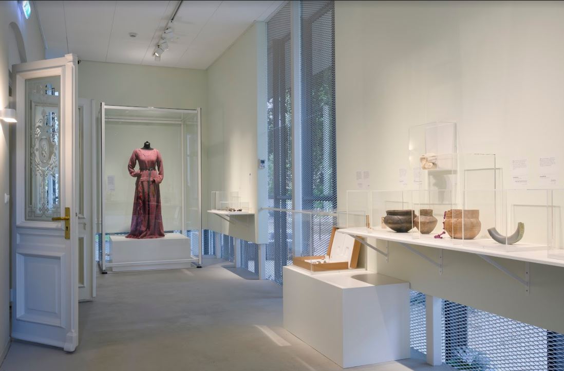 Foto van een zaal in Museum Jan Cunen met daarin de reconstructie van de oudste jurk tentoongesteld.
