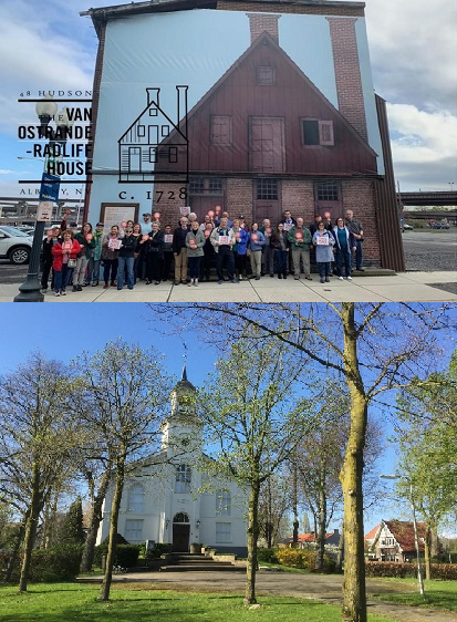 Building with a group of people in front of it, and white church behind some trees